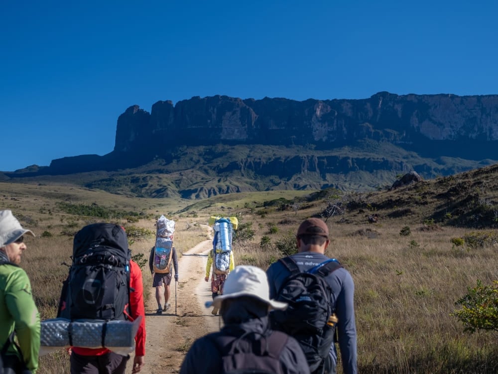 Trekkers with backpacks approaching Mount Roraima on the trek across the Gran Sabana Trekkers with backpacks approaching Mount Roraima on the trek across the Gran Sabana