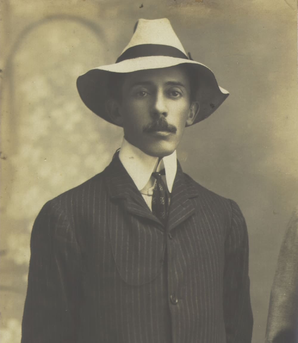 Photo: Museu Paulista (USP) Collection Sepia studio portrait of Brazilian aviation pioneer Santos Dumont wearing a white hat and a pinstripe suit