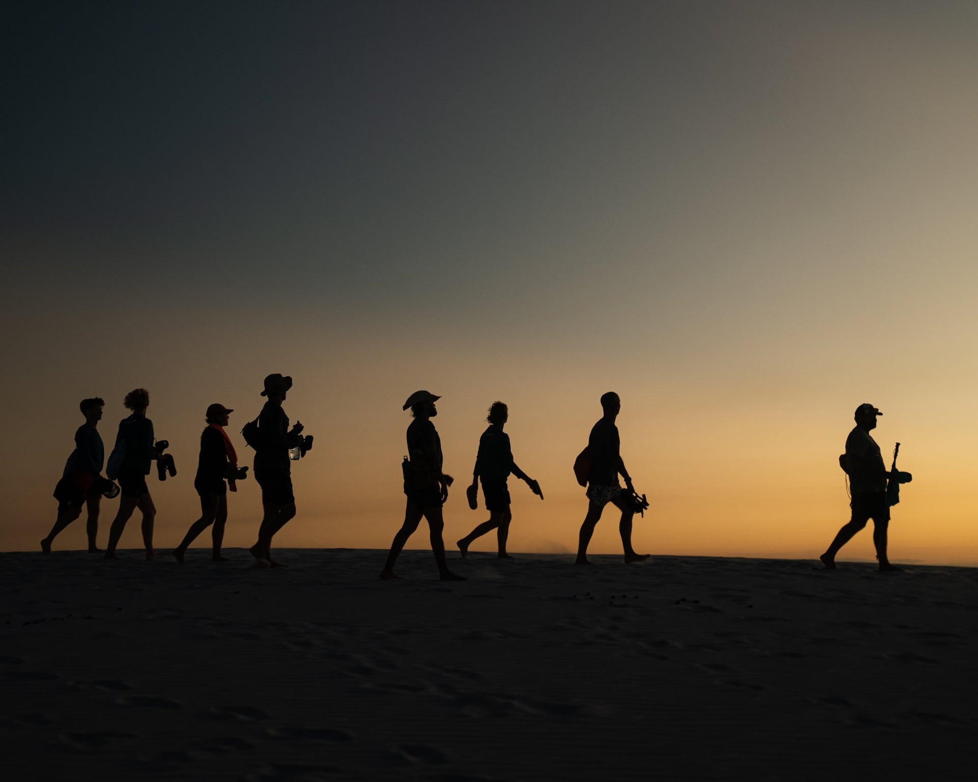 Silhouettes of a small trekking group walking across the Lençóis Maranhenses dunes at sunset Silhouettes of a small trekking group walking across the Lençóis Maranhenses dunes at sunset