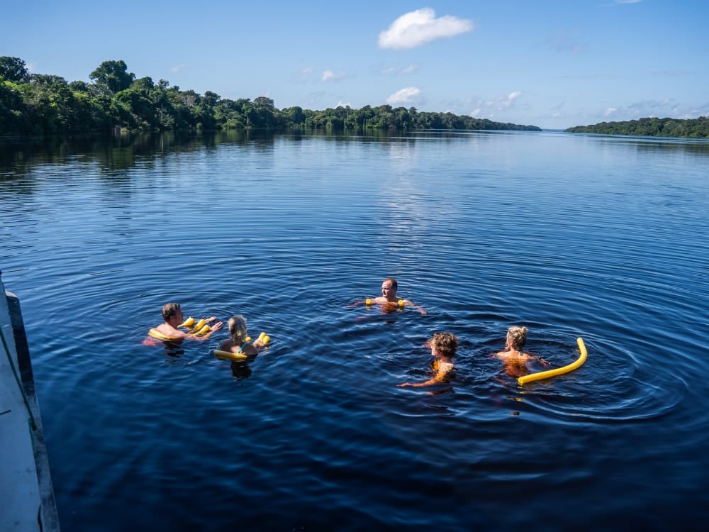 Photo: Felipe Castellari Voyageurs se baignant avec des flotteurs à côté du bateau dans le fleuve Amazone, au Brésil
