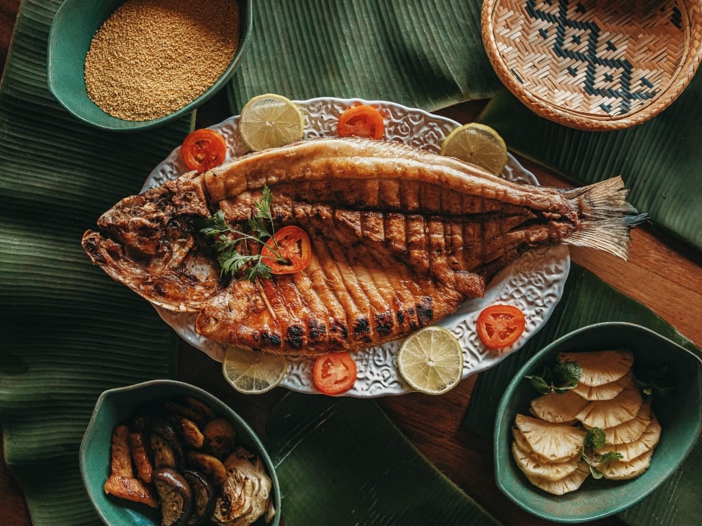 Photo: Felipe Castellari Poisson grillé entier servi sur des feuilles de bananier avec farofa, citron vert et tomate, en Amazonie brésilienne