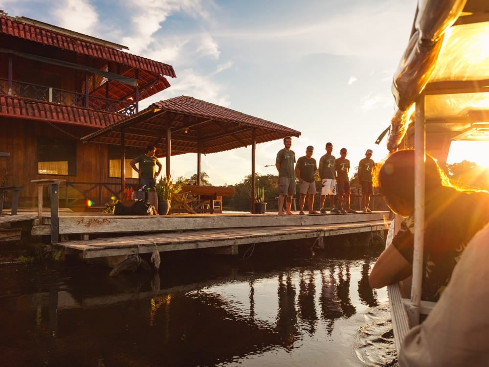 Photo: Gui Gomes Staff waiting on the wooden deck of Uakari Floating Lodge at sunset as a boat arrives