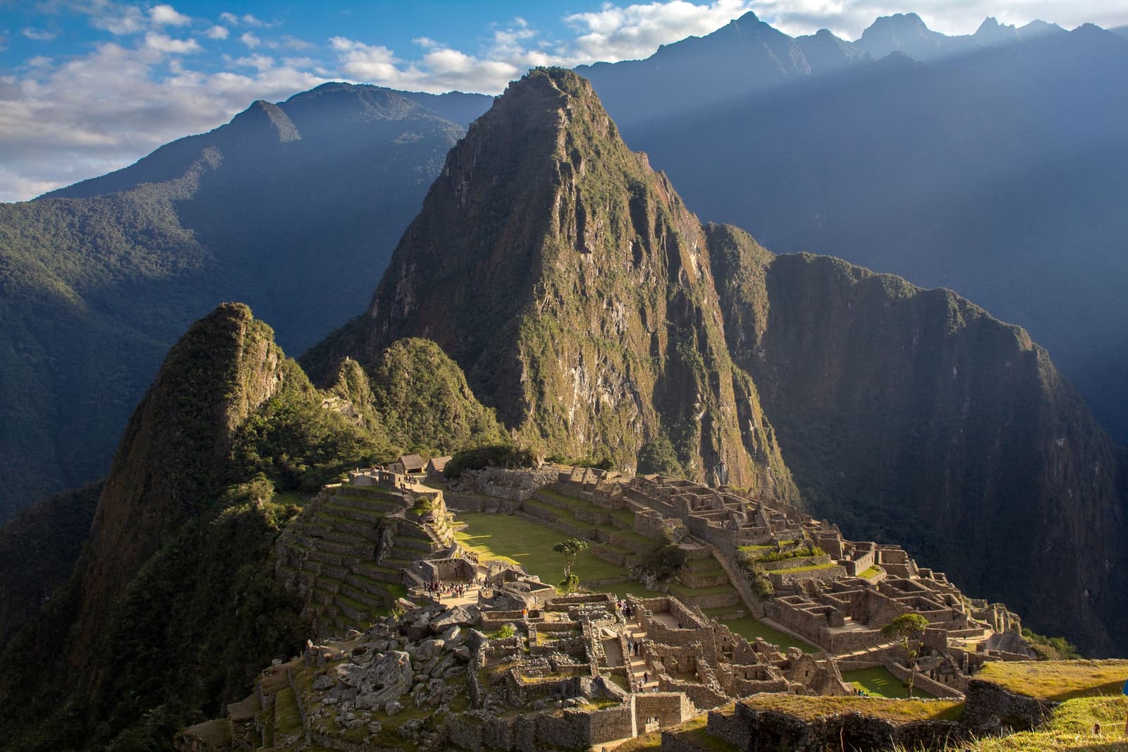 Inca engineers picked the most dramatic ridge they could find, and honestly, fair enough. Panoramic view of the Machu Picchu citadel with Huayna Picchu mountain rising sharply behind the Inca stone terraces and ceremonial plazas, on a machu picchu amazon tour that crosses Peru from rainforest to the Andes