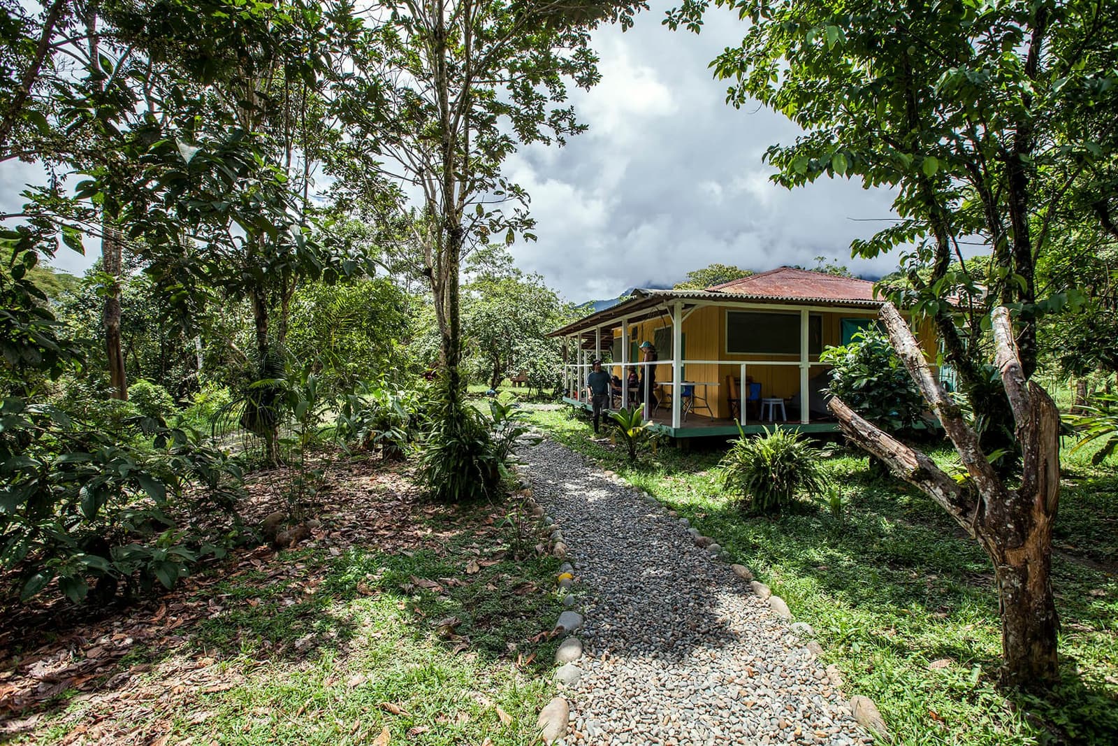 Good things happen on the porch here, with the Araza River just steps away. A gravel and river-stone path leads through lush cloud-forest gardens to a yellow timber lodge with a red corrugated roof and covered veranda, part of the overland machu picchu amazon tour route between the rainforest and the Andes