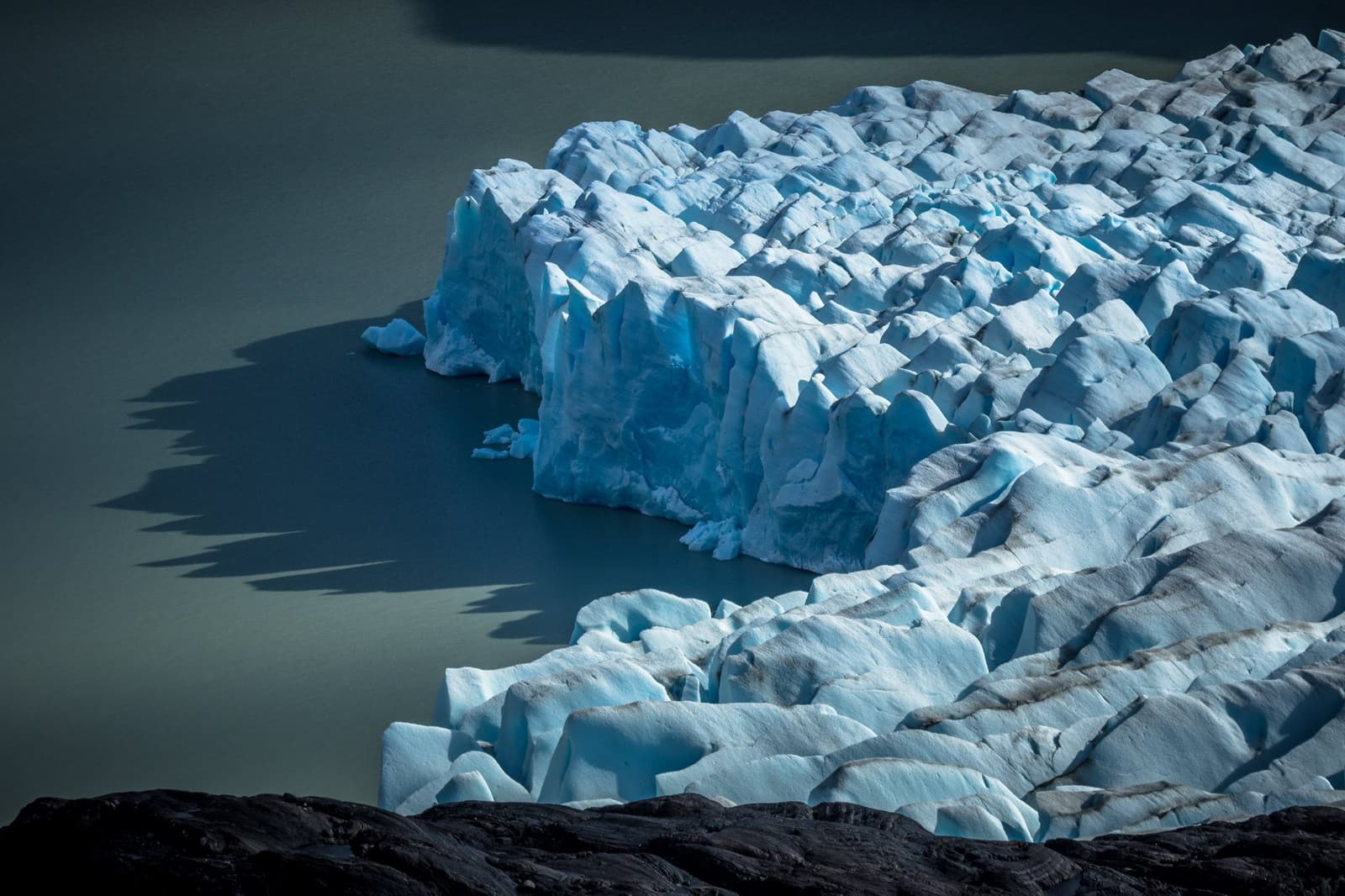 Ice this old has earned its shade of blue. You just have to walk to it. Photo: outdoorstv.cl Jagged blue-white ice towers at the calving front of Grey Glacier meeting a dark glacial lake, seen from above on the self-guided O Circuit in Torres del Paine