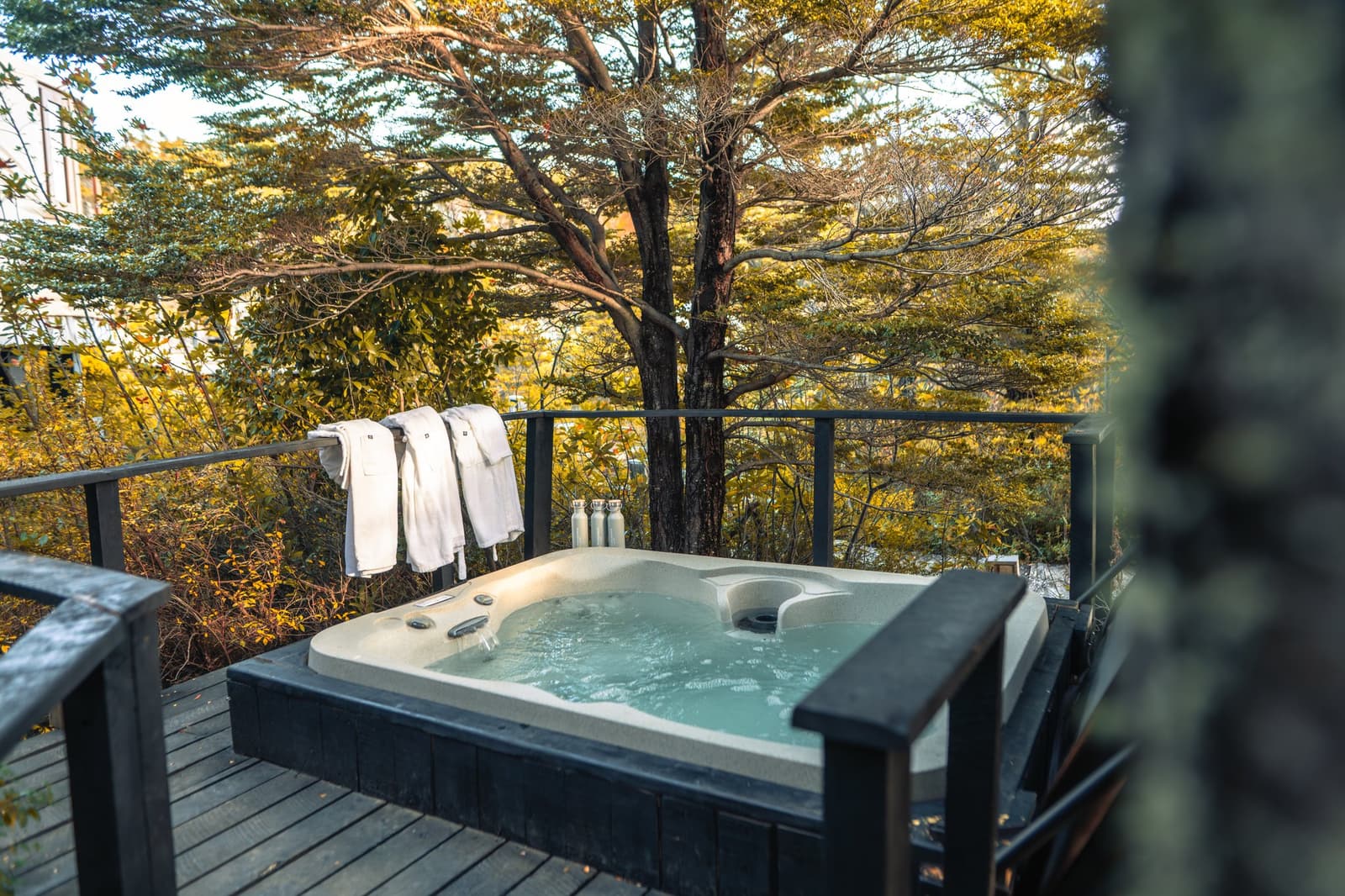 A soak in the trees, with Patagonia doing the rest. Photo: Patagonia Camp A bubbling outdoor jacuzzi on a dark-wood deck at Patagonia Camp, with white robes draped over the railing and autumn-toned native forest stretching into the background