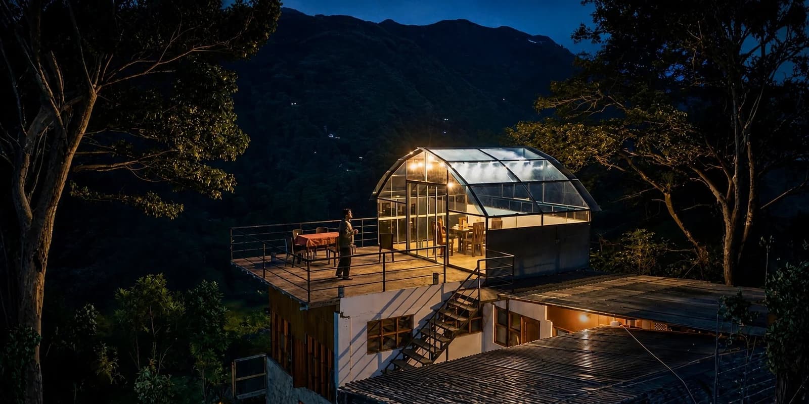Dinner with a mountain backdrop, no tent poles required. A glass-roofed dome lodge lit from within at dusk on the Salkantay trek to Machu Picchu, with a person standing on the open terrace and dark forested mountains rising behind