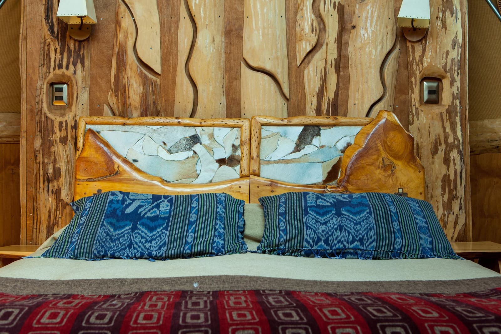 Every detail in the dome was made by someone's hands, and it shows. Photo: Superior Dome Handcrafted wood and patchwork hide headboard with indigo woven pillow covers on a bed inside an eco-dome on a torres del paine 4 day all inclusive tour