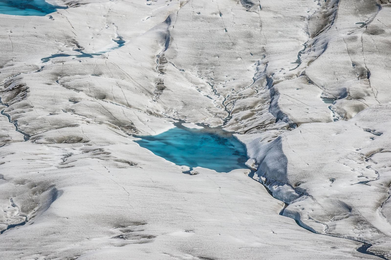 A glacier carving its own plumbing, one blue pool at a time. Photo: outdoorstv.cl Aerial view of vivid turquoise meltwater pools and channels carved into a vast white glacier surface, seen on the self-guided O Circuit in Torres del Paine