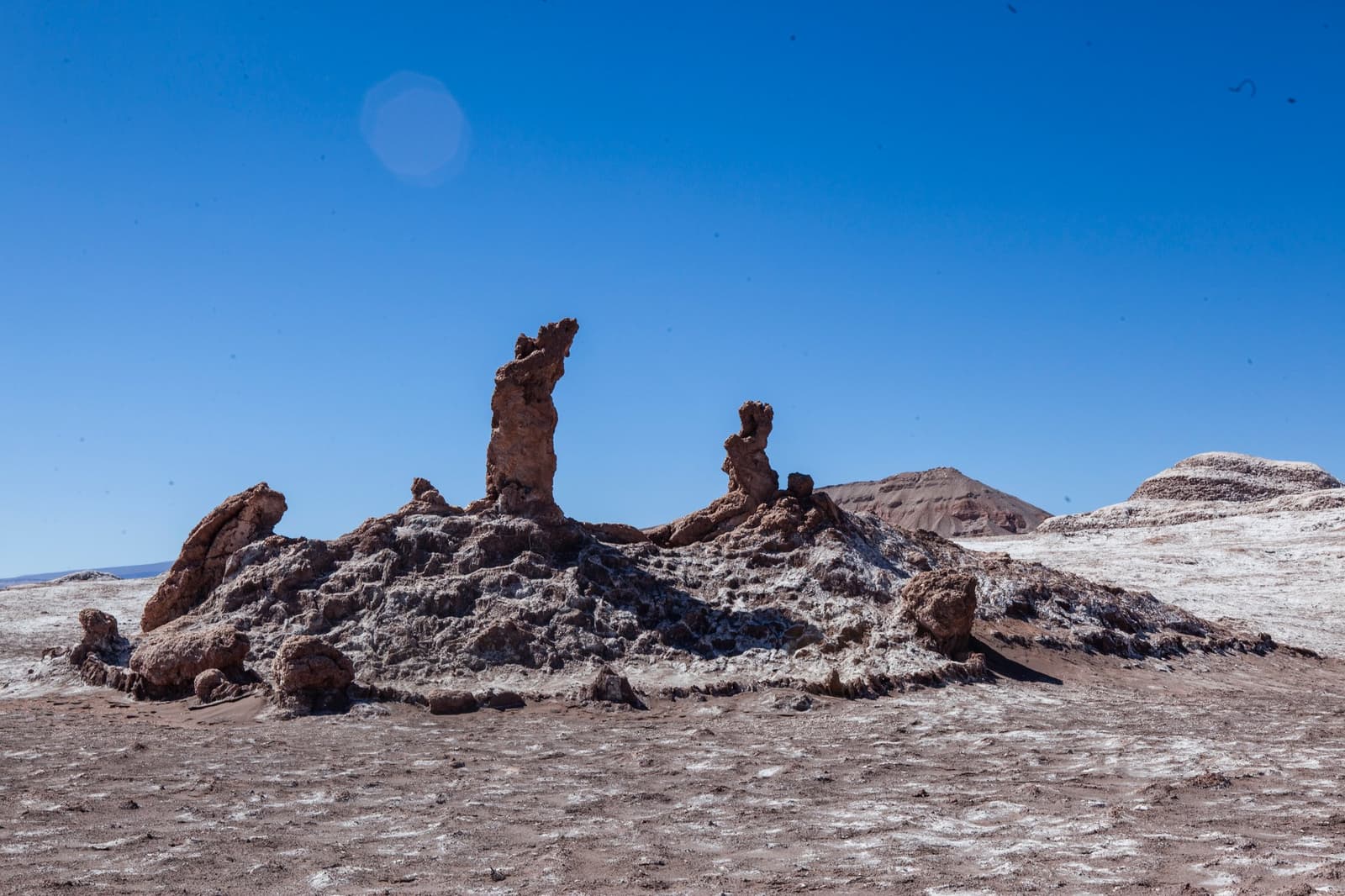 Millions of years of wind and salt, doing what no sculptor would dare. Photo: Tres Marias Eroded salt and rock pinnacles of the Tres Marías formations rise from a white-crusted mound in Valle de la Luna, part of this atacama desert tour package, under a deep blue sky with barren hills behind