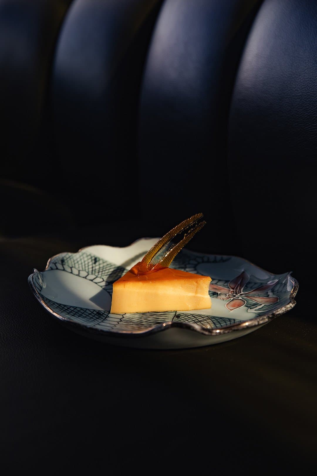 Small plate, big finish. The kitchen doesn't phone it in. Photo: Yvonne Kreuzmayr A slice of golden flan topped with caramel and a candied garnish, plated on a hand-painted porcelain dish aboard the Aria Amazon cruise
