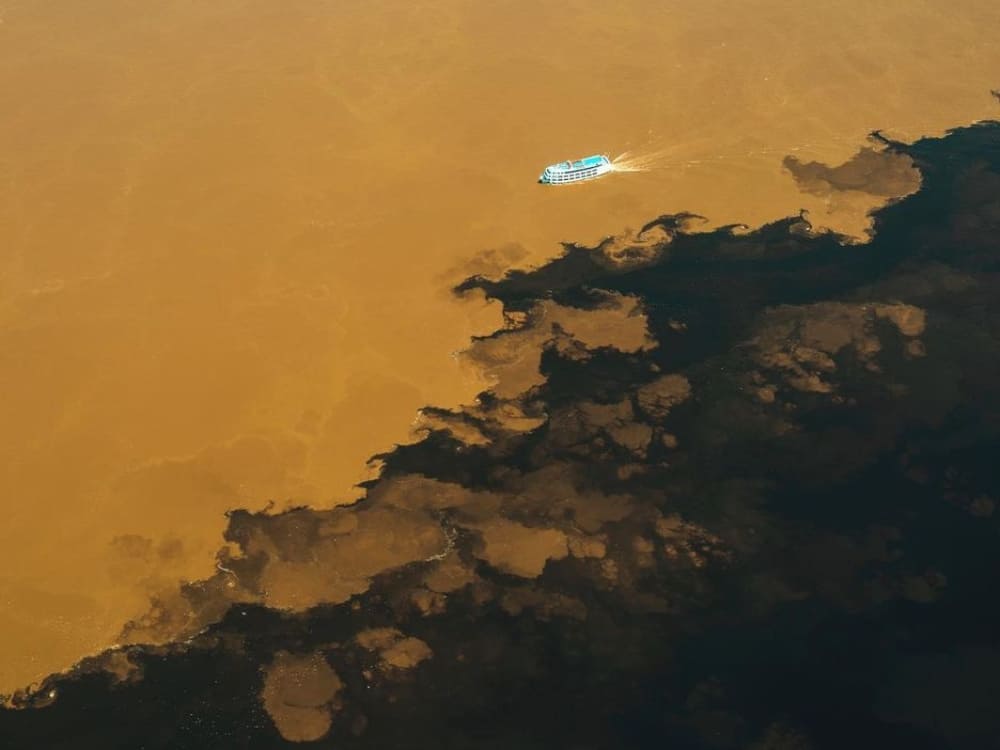 Luchtfoto die de duidelijke scheidslijn toont waar de zwarte Rio Negro de bruine Solimões-rivier ontmoet.