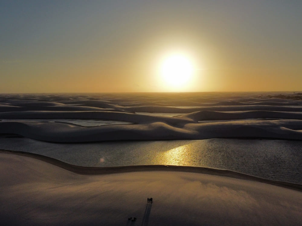 Die Sonne geht leuchtend über den weißen Sanddünen und Regenwasserlagunen im Nationalpark unter.