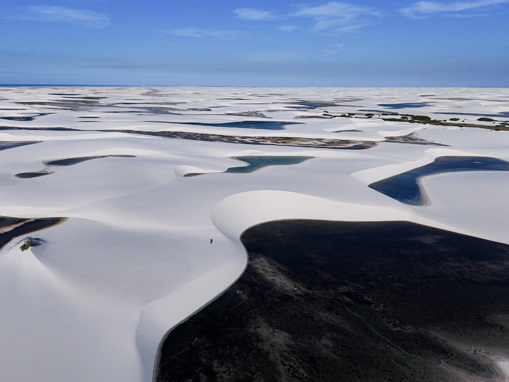  A wide landscape shows thousands of rainwater lagoons interspersed among the white sand dunes. 