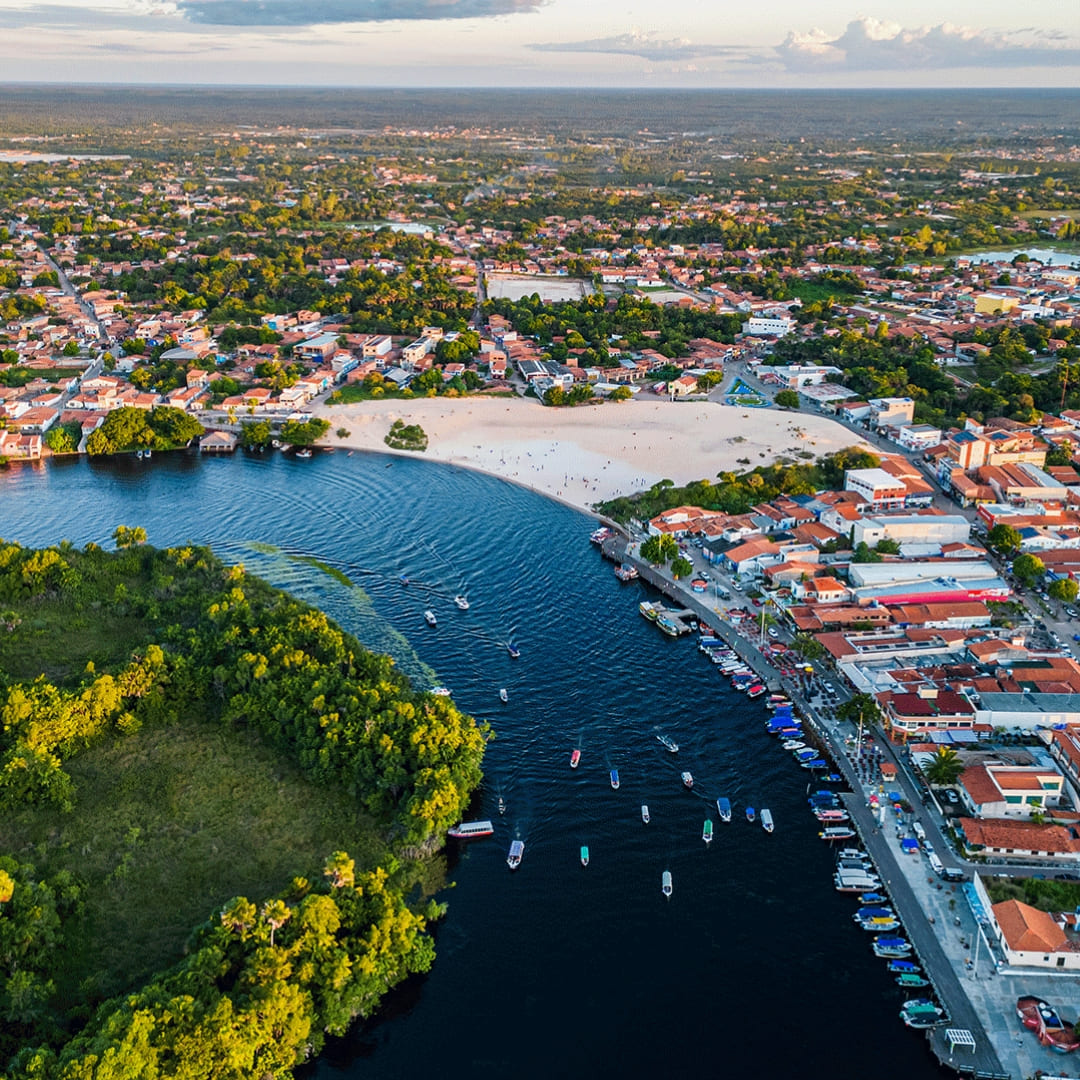 Luftaufnahme der Stadt Barreirinhas, mit Fokus auf die Flussschleife des Preguiças-Flusses und Sandabschnitte, die den Haupteingang zum Park veranschaulichen.