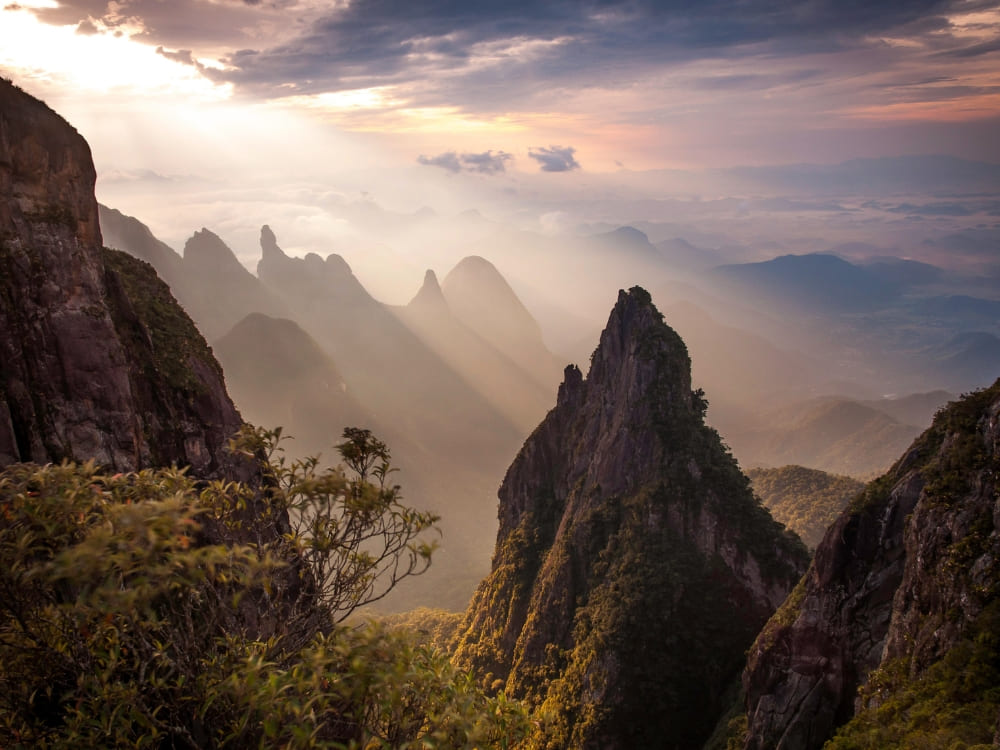 Lever de soleil brumeux sur les pics montagneux déchiquetés et les sentiers du parc national de la Serra dos Órgãos au Brésil.