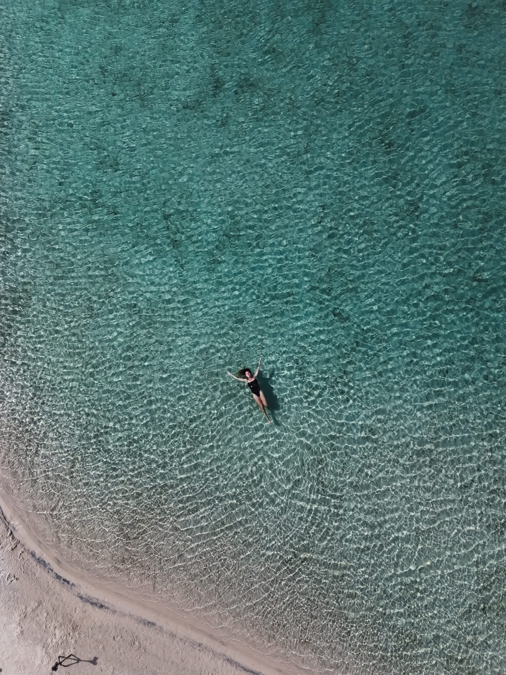 Vue de dessus d'une femme flottant dans les eaux calmes et verdâtres d'une lagune exclusive lors d'un voyage aux Lençóis Maranhenses.