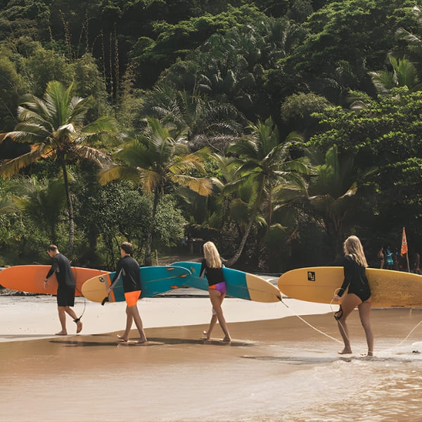 Vier mensen met kleurrijke surfplanken lopen naar de oceaangolven op een strand in Itacare.