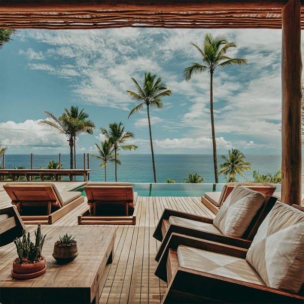 Elegante houten stoelen op een terras bij het zwembad met uitzicht op palmbomen en de zee in Bahia.