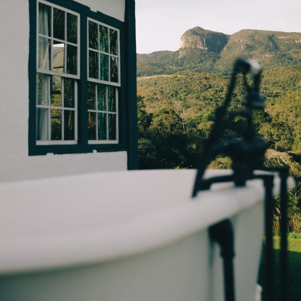 Wit buitenbad met een schilderachtig uitzicht op een bergketen tijdens een luxe vakantie.