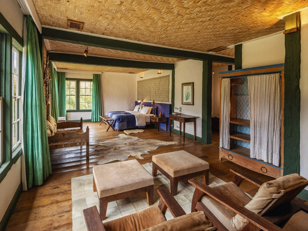 Ruime rustieke slaapkamer met een groot bed, houten vloeren en groene accenten bij het Ibiti Project.