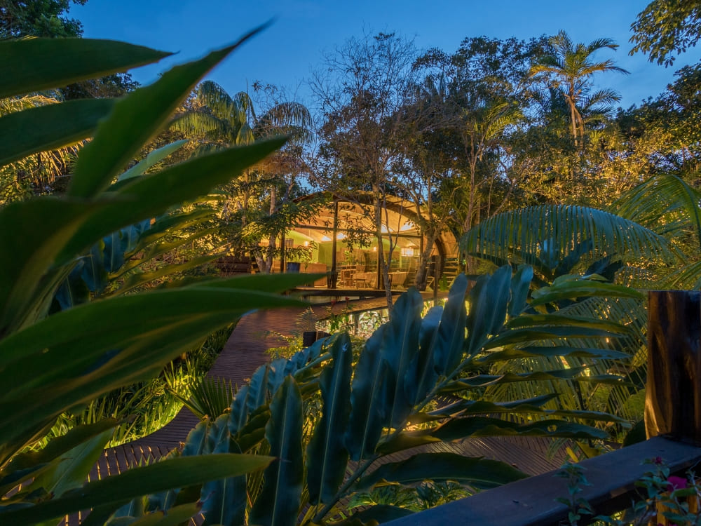 Verlichte houten bungalow bij Mirante do Gaviao Amazon Lodge, 's nachts omringd door bomen.