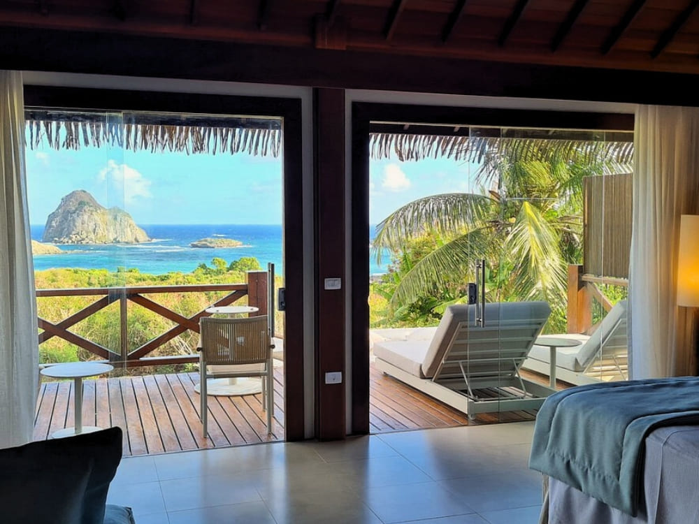 Open balkondeuren onthullen een ligstoel en een prachtig uitzicht op de oceaan in Fernando de Noronha.