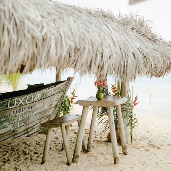 Rustieke houten tafel en boot onder een rieten parasol op het witte zand van het strand van Trancoso.
